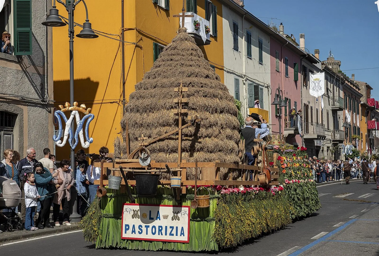 Il carro della pastorizia con un grande covone di paglia sfila tra le case colorate di Marta durante la Barabbata